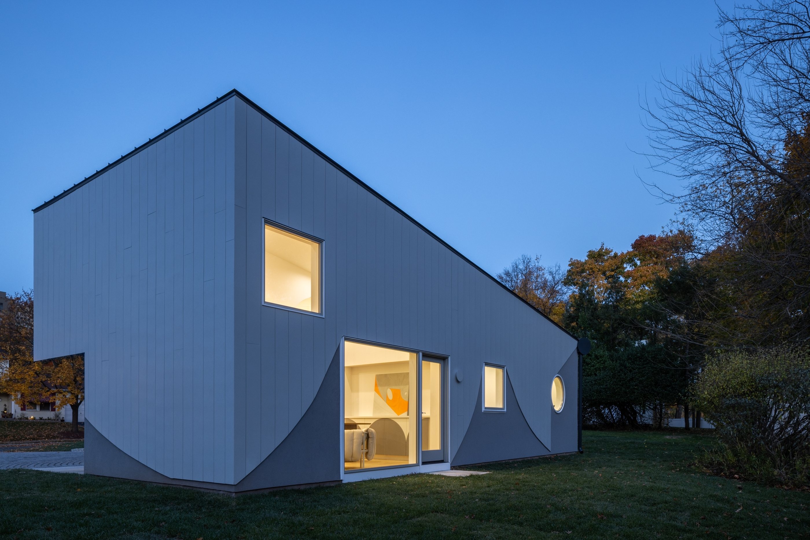 The Swoop ADU at dusk seen from the backyard, the living area glowing through the sliding doors